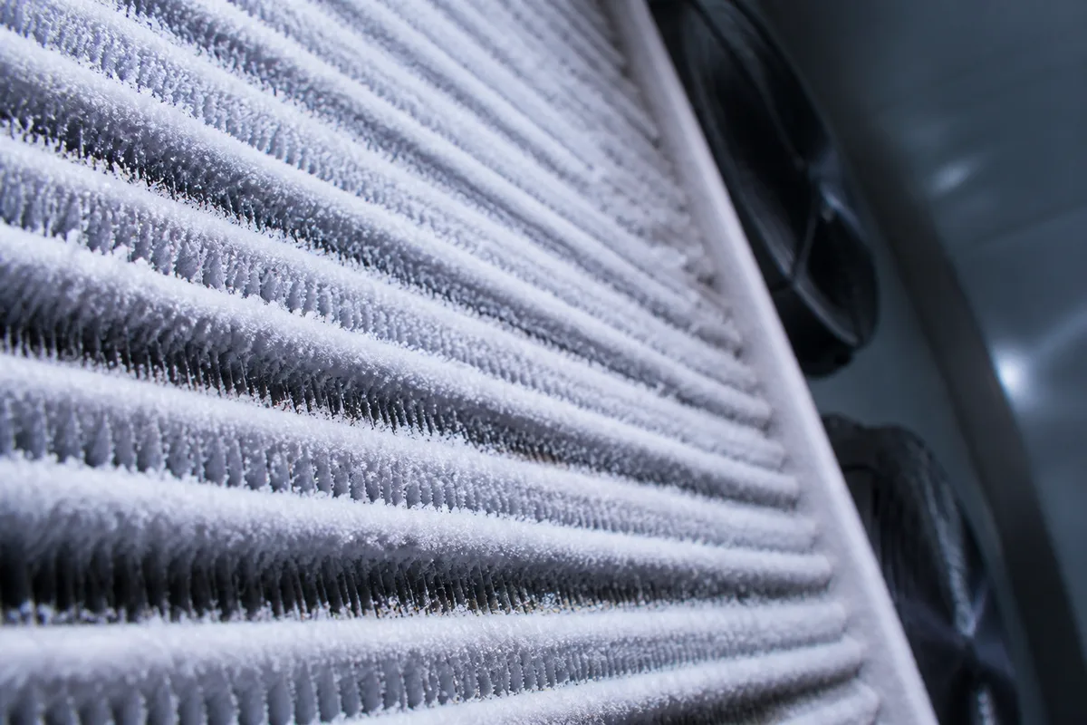 Détail technique d&rsquo;un évaporateur de chambre froide couvert de givre, éclairage froid et rasant