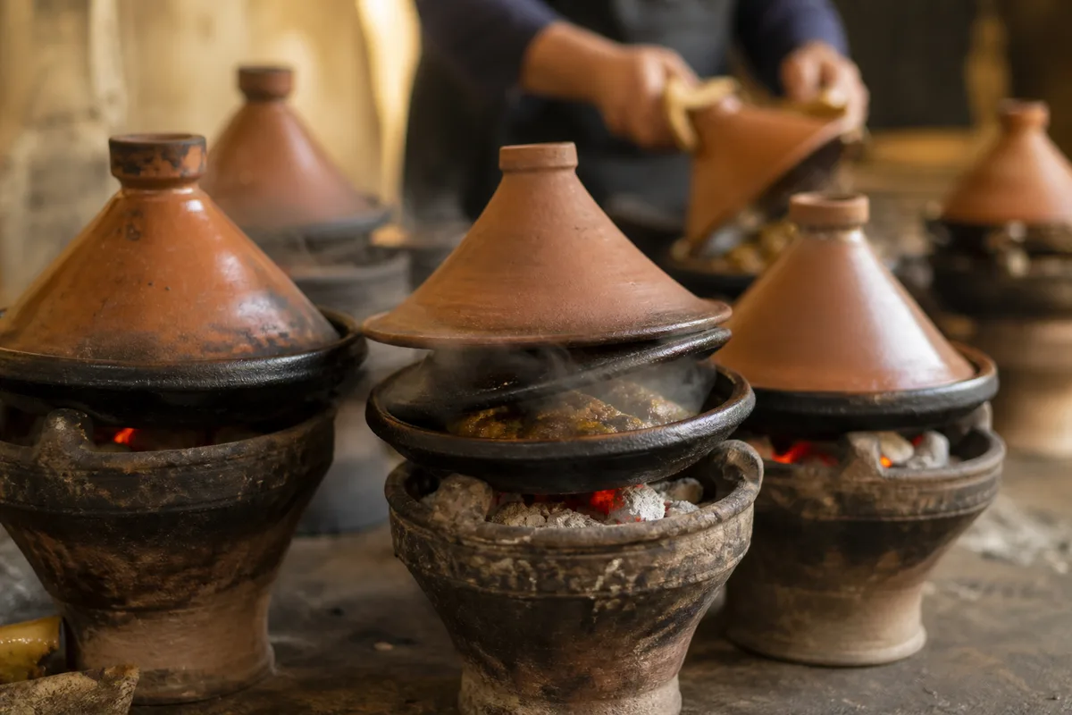 Tajines en terre cuite mijotant sur des braises dans une cuisine marocaine
