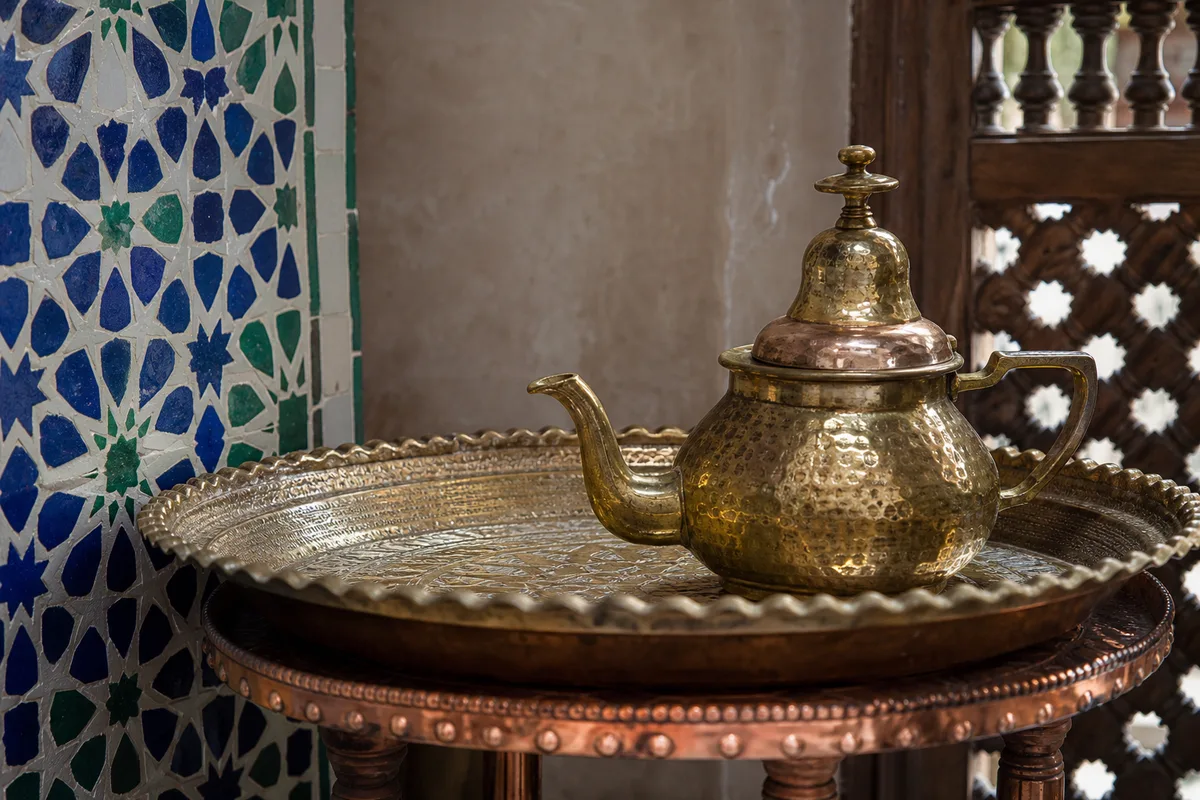 Détail d&rsquo;artisanat marocain avec zellige coloré, panneau moucharabieh en bois et plateau en laiton martelé